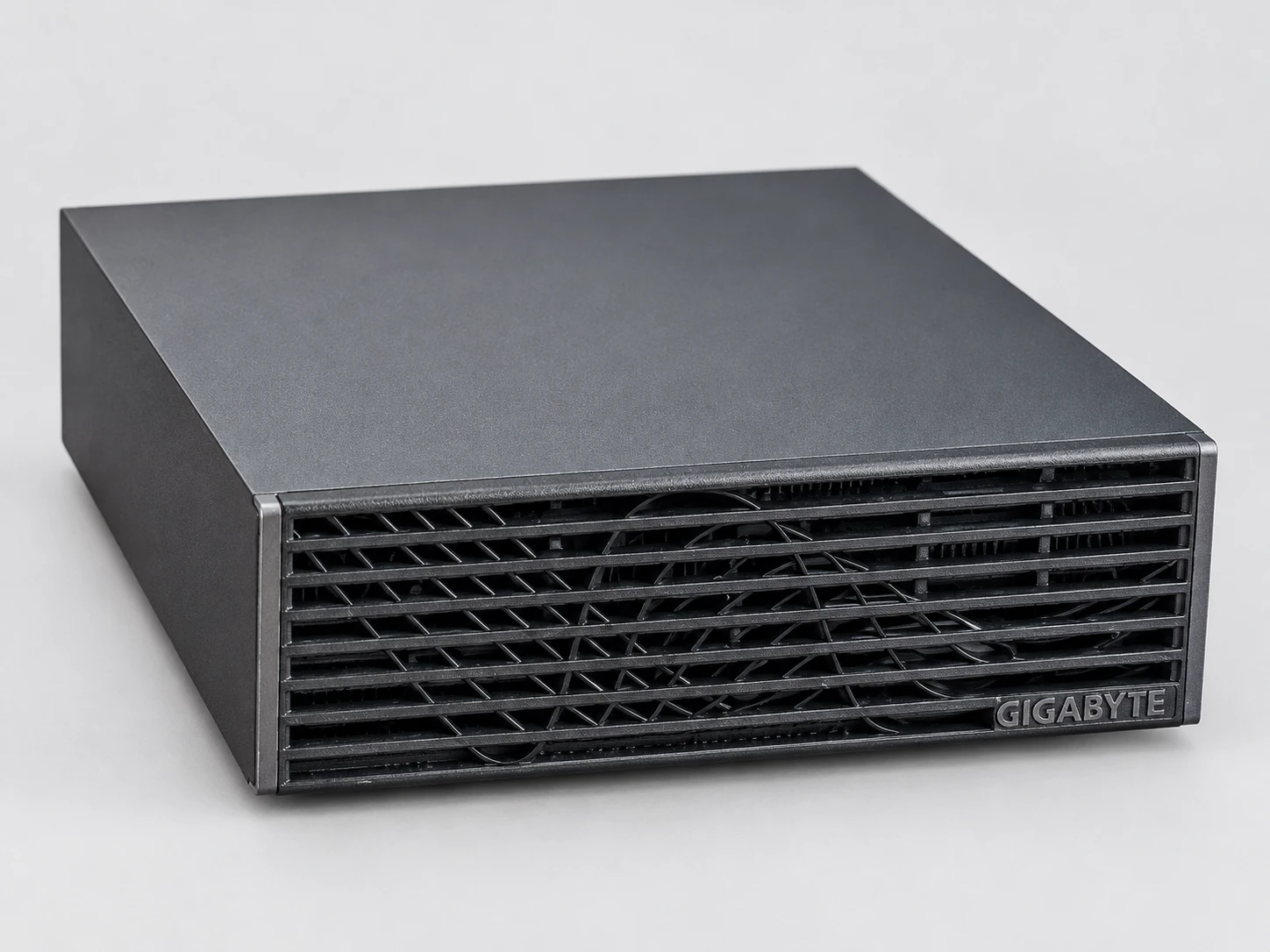 The GIGABYTE AI TOP ATOM viewed from the front-right at a three-quarter angle, lying flat: anthracite-gray cover and black slatted front panel.